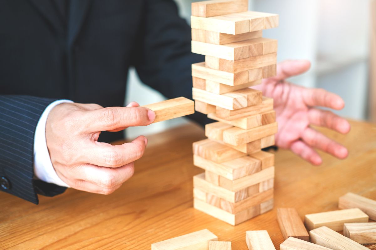 business person pulling brick from a game of Jenga - Risks of Running SharePoint Server 2013 Unsupported